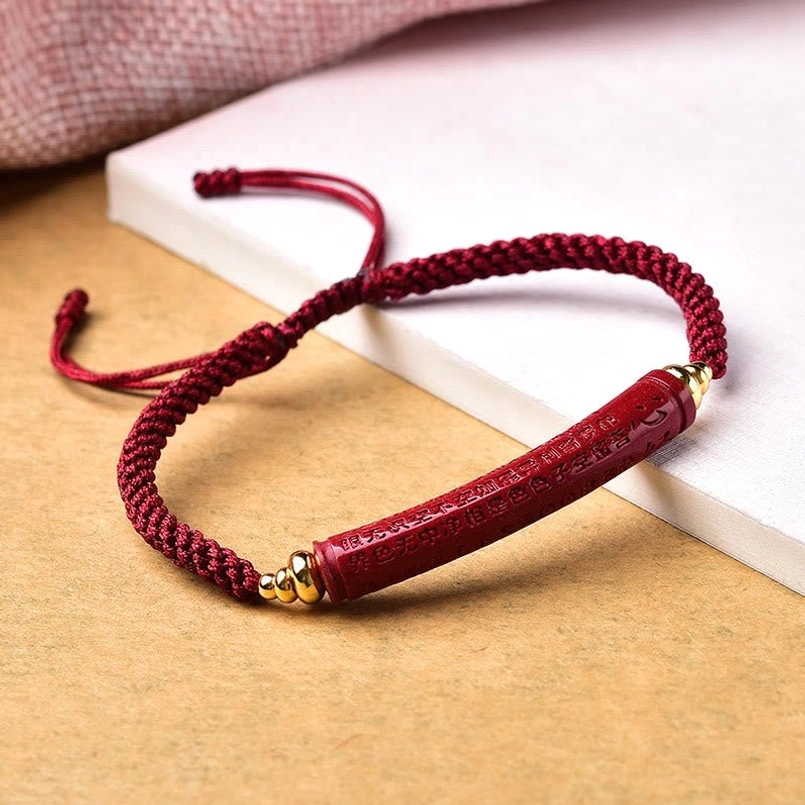 Heart Sutra engraved cinnabar red string bracelet front view on wooden table