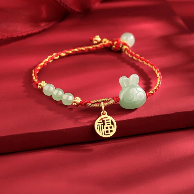 Close-up of Hetian jade beads and gold decorative accents on red string bracelet