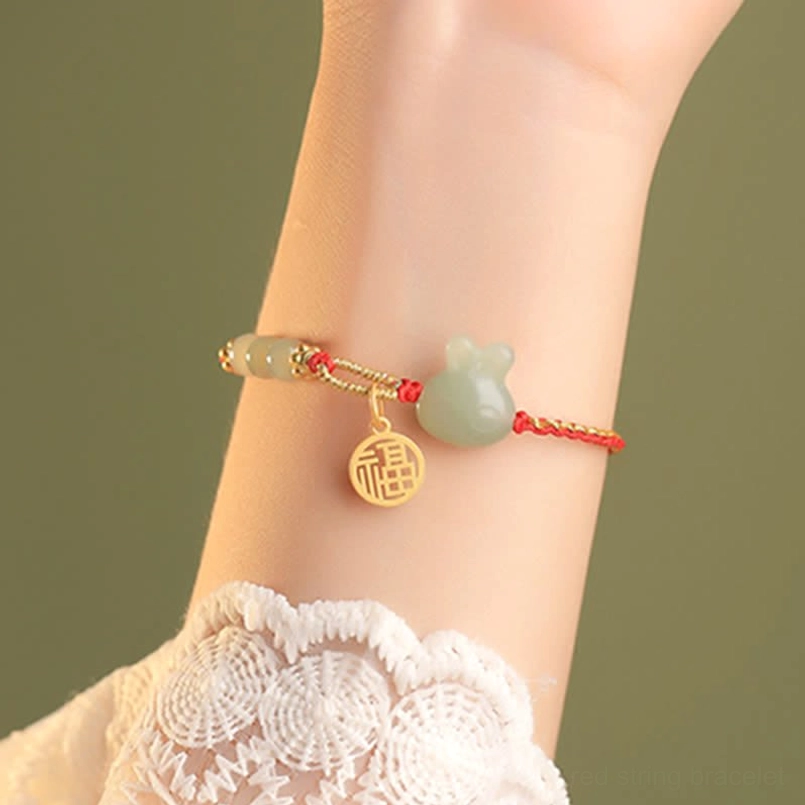 Red string Hetian jade bracelet close-up fitted on wrist with lace cuff