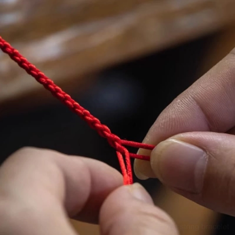 Artisan hands knotting five-colored blessed string, demonstrating handmade craftsmanship of jade bracelet