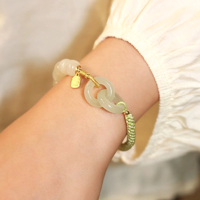 Hetian jade double peace buckle bracelet side close-up showing pale interlocking jade rings with gold drop charm