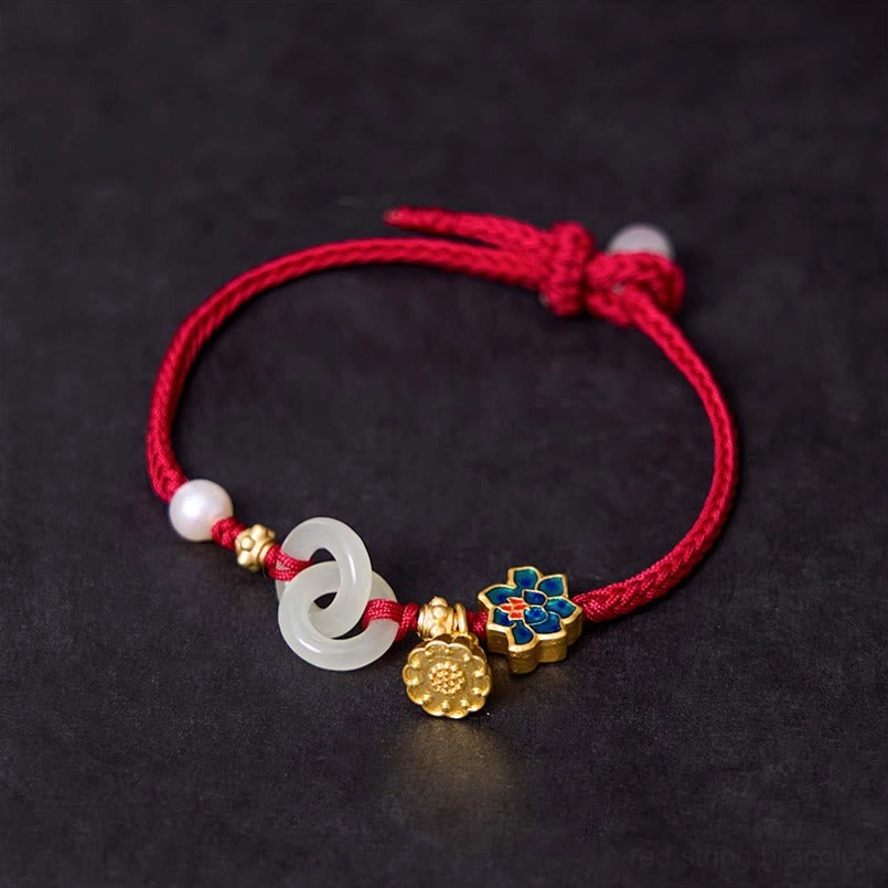 Red cord Hetian jade bracelet with interlocked jade peace buckle rings and enamel lotus charm flat lay