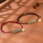 Hetian jade lotus pod red and black string bracelets flat lay on warm wooden table