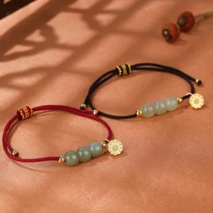 Hetian jade lotus pod red and black string bracelets flat lay on warm wooden table