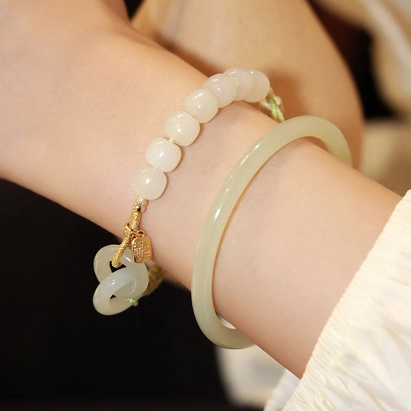 Arm wearing multiple pieces Hetian jade beaded bracelet with interlocking jade charm and pale green jade bangle