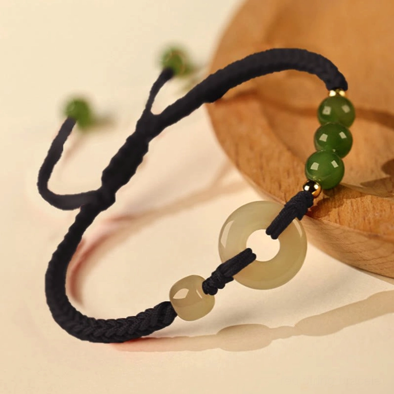 Hetian Jade Peace Buckle Black String Bracelet Close Up On Wooden Coaster