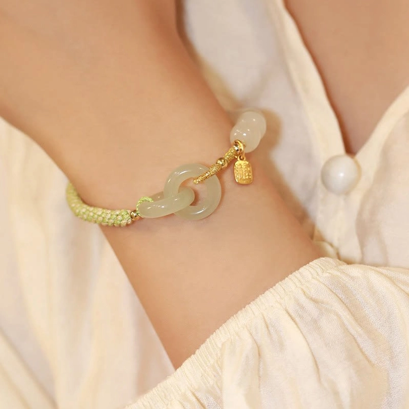 Hetian jade double peace buckle bracelet wrist wear showing small extra jade bead accent with green braided cord