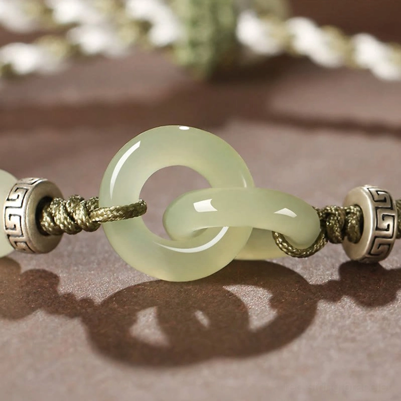 Detailed close-up of light green jade peace buckles with engraved metal beads and braided cord texture