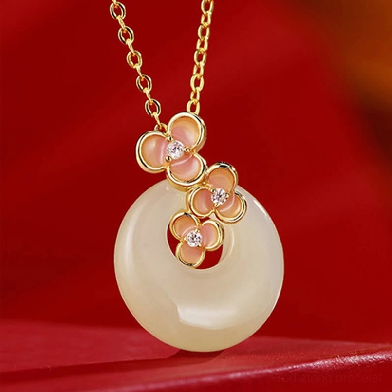 Hetian jade peace buckle necklace pendant with floral cubic zirconia and gold-toned metal on red fabric