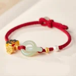 Red braided Hetian jade peace buckle fortune bracelet with lotus charm and pearl accent on light background