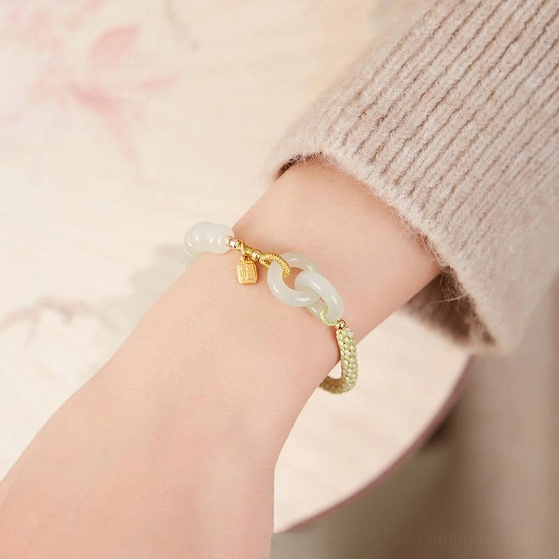 Side view of Hetian jade double peace buckle bracelet on wrist with pale green jade and gold charm pendant