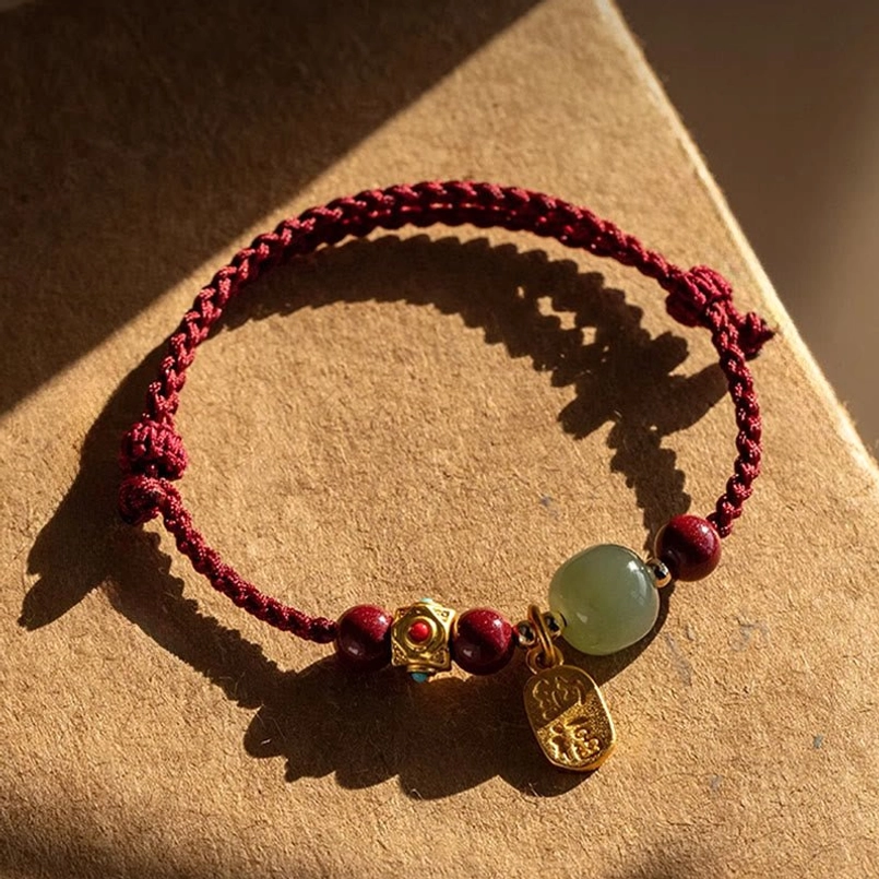 Braided prosperity bracelet with five-colored string displayed on natural craft surface with sunlight shadow