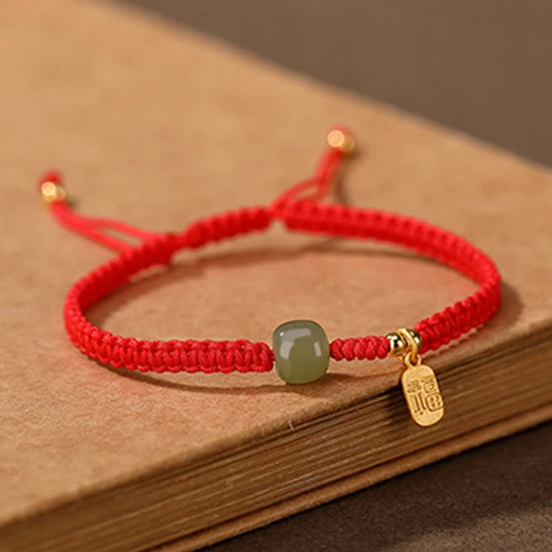 Red woven fortune bracelet featuring smooth Hetian jade bead and gold accent