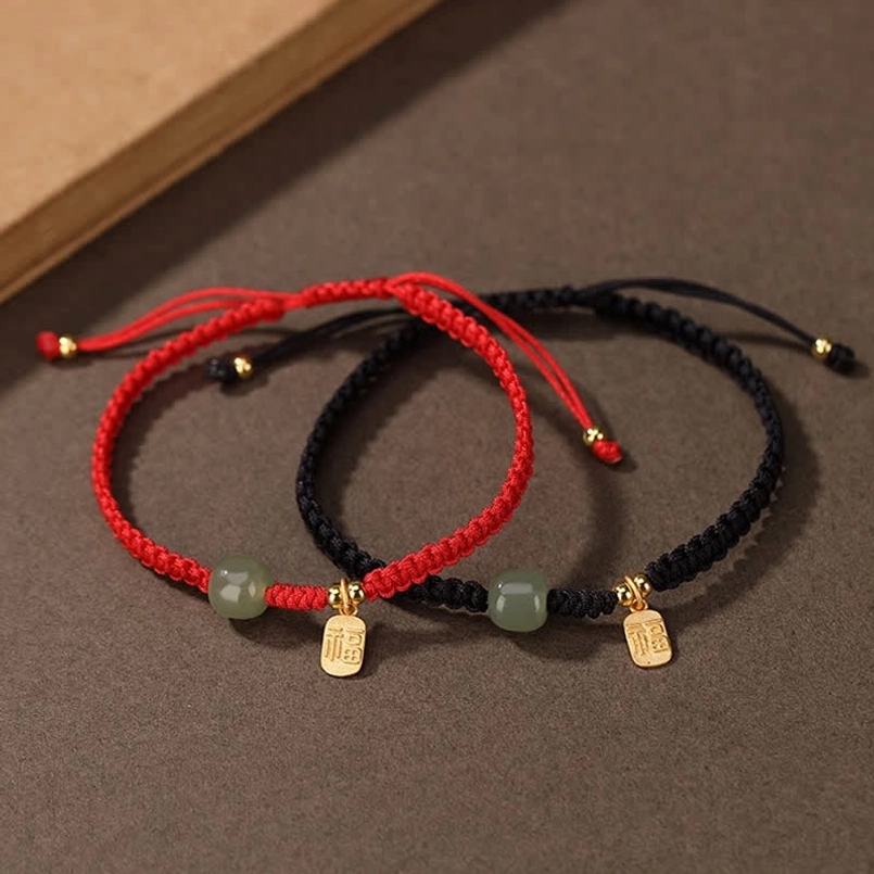 Hetian jade red and black string bracelets with gold fu charm - top-down flat lay view