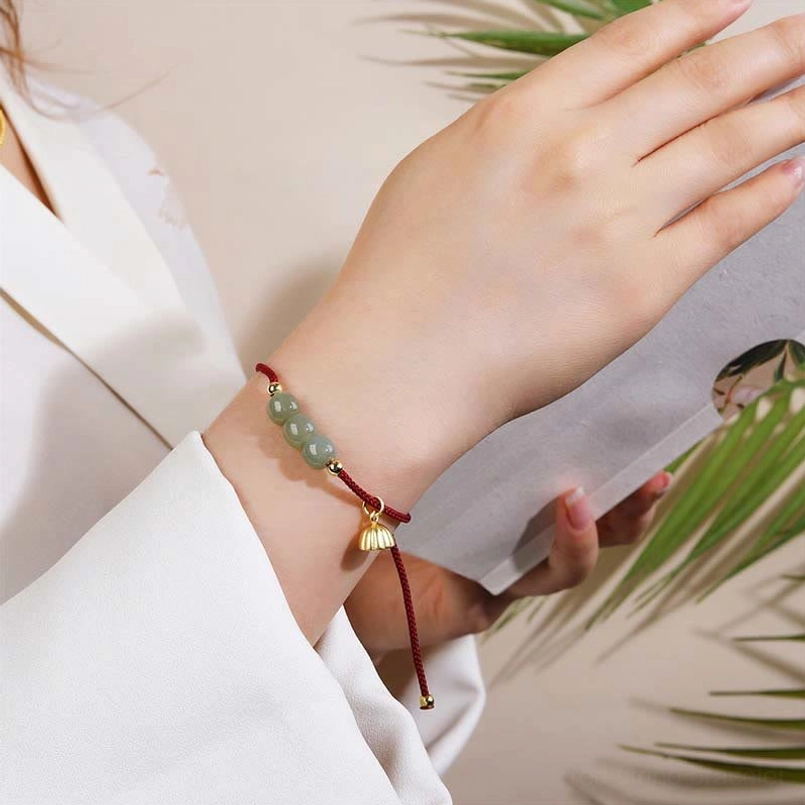 First person view of Hetian jade lotus pod red string bracelet worn on wrist