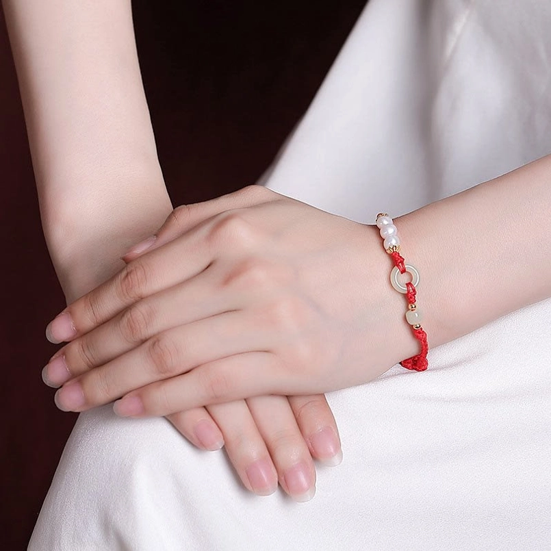 Red string peace buckle bracelet worn on left wrist close up shot