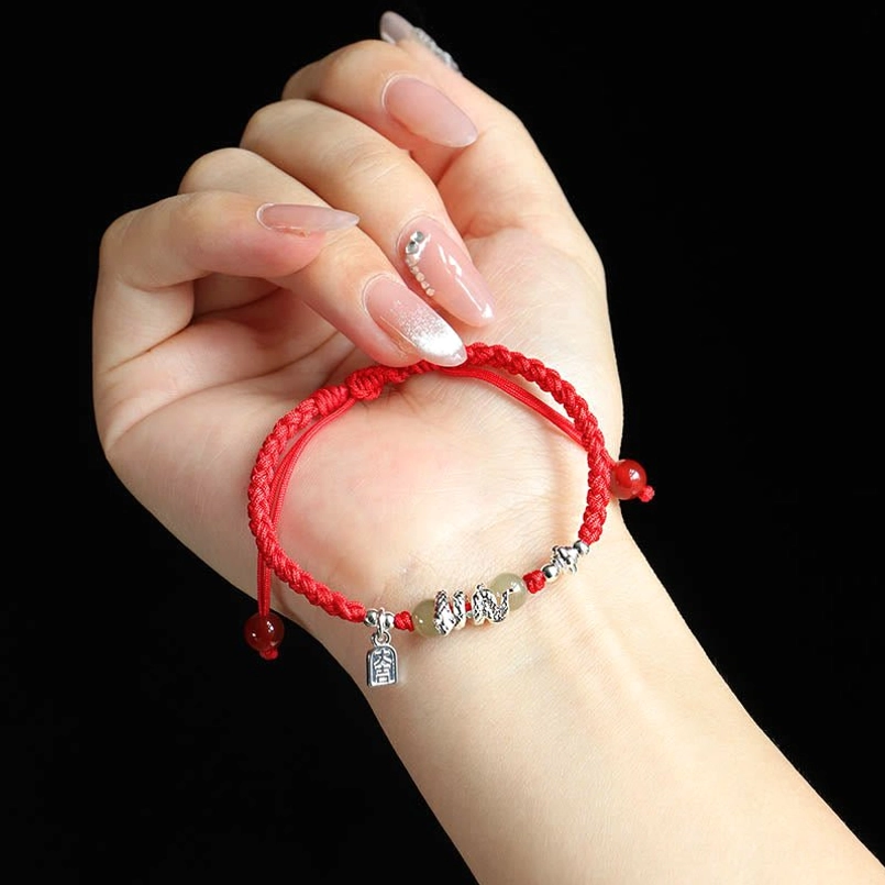 Red string jade bracelet worn on wrist close-up with silver snake charm
