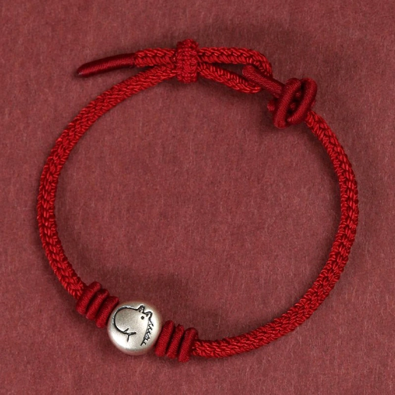 Full circular braided red string horse bracelet with adjustable sliding knot, overhead flat lay