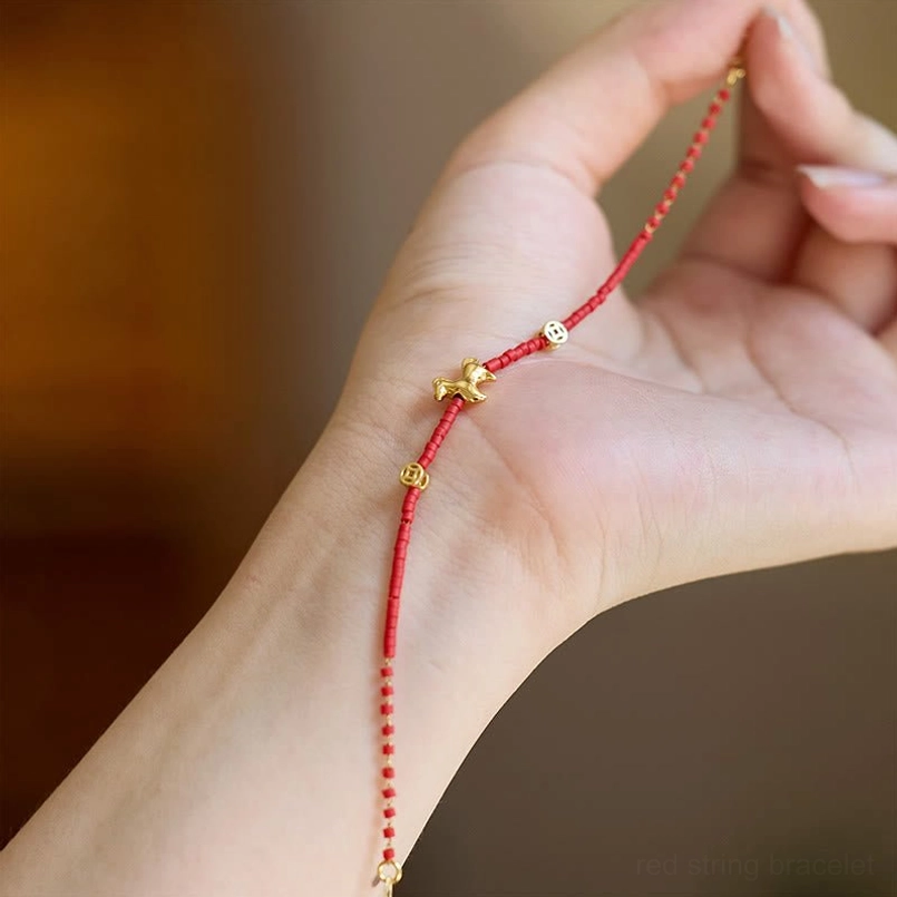 Hand holding Year of the Horse red liuli bracelet showing detailed bead and charm work