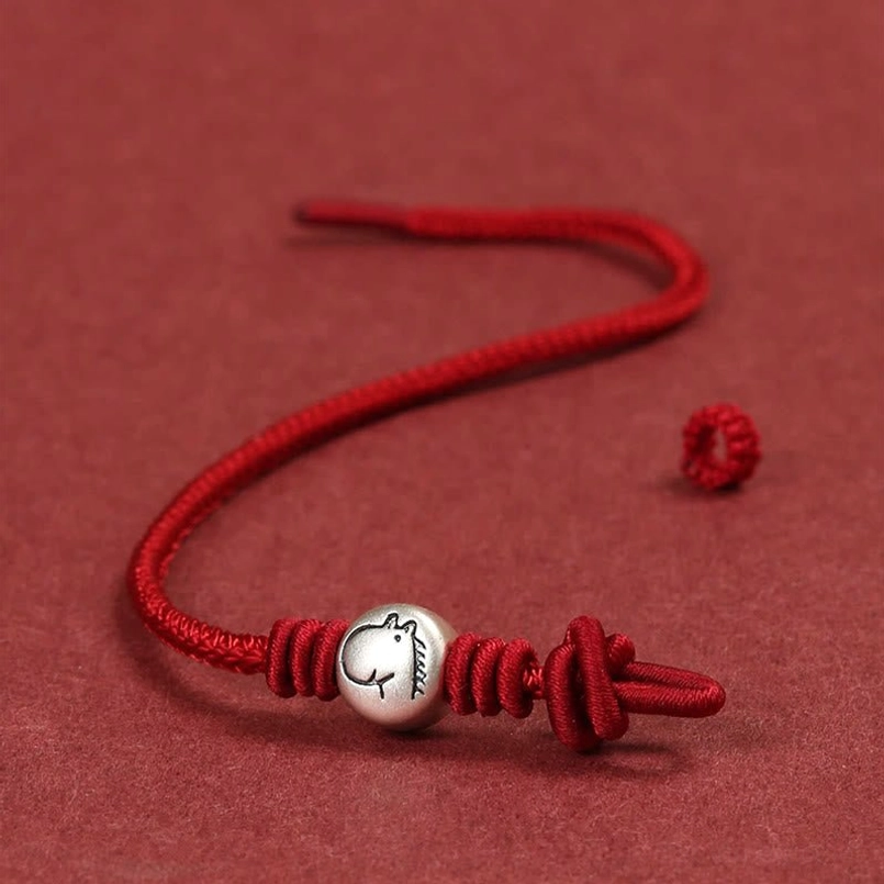 Unstrung loose sterling silver horse bead with red cord ends, adjustable components flat lay