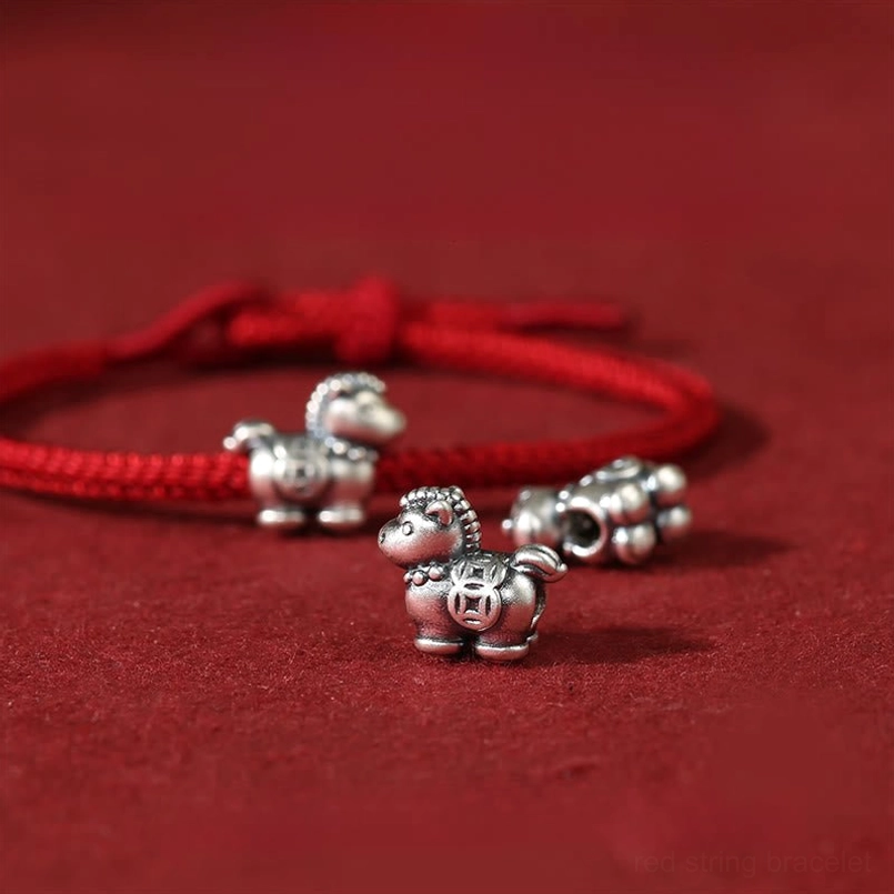 Multiple Year of the Horse red string bracelets and silver charms laid out display