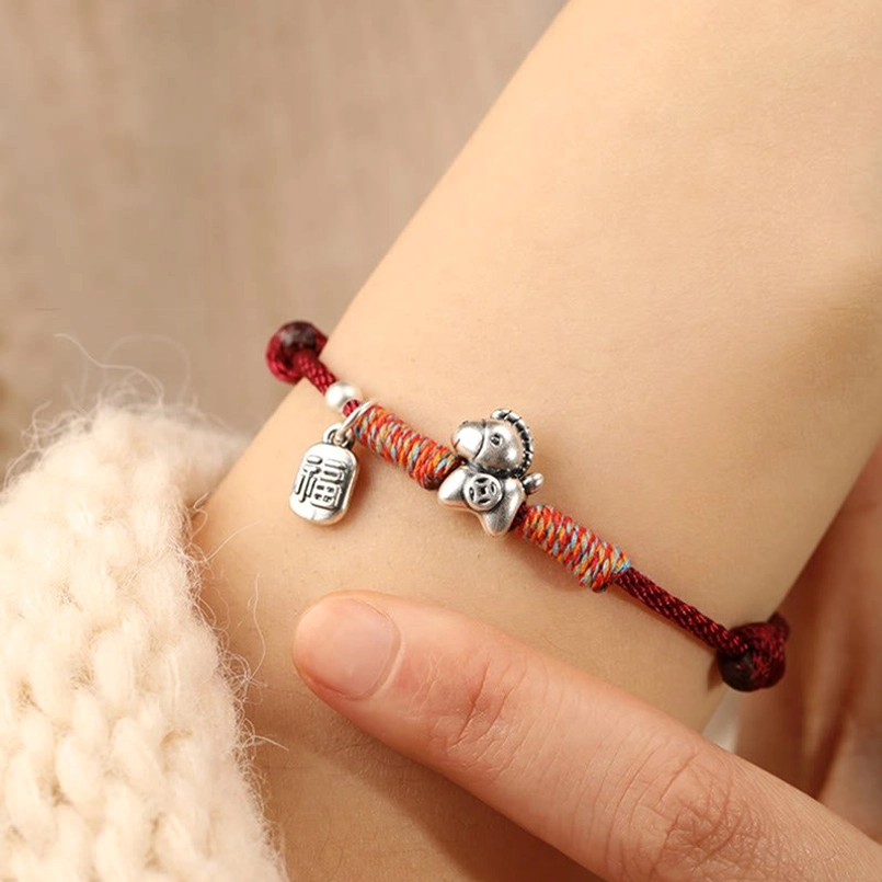 First-person wrist view of Year of the Horse fu character silver red string bracelet worn on arm with sleeve