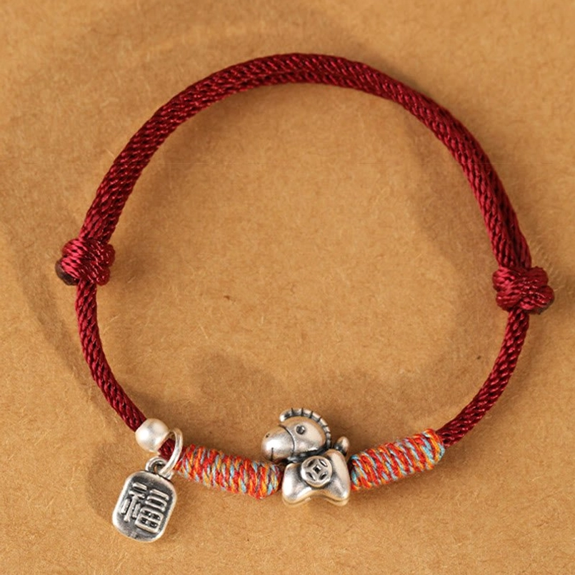 Maroon braided rope Year of the Horse sterling silver fu pendant and charm bracelet on brown paper