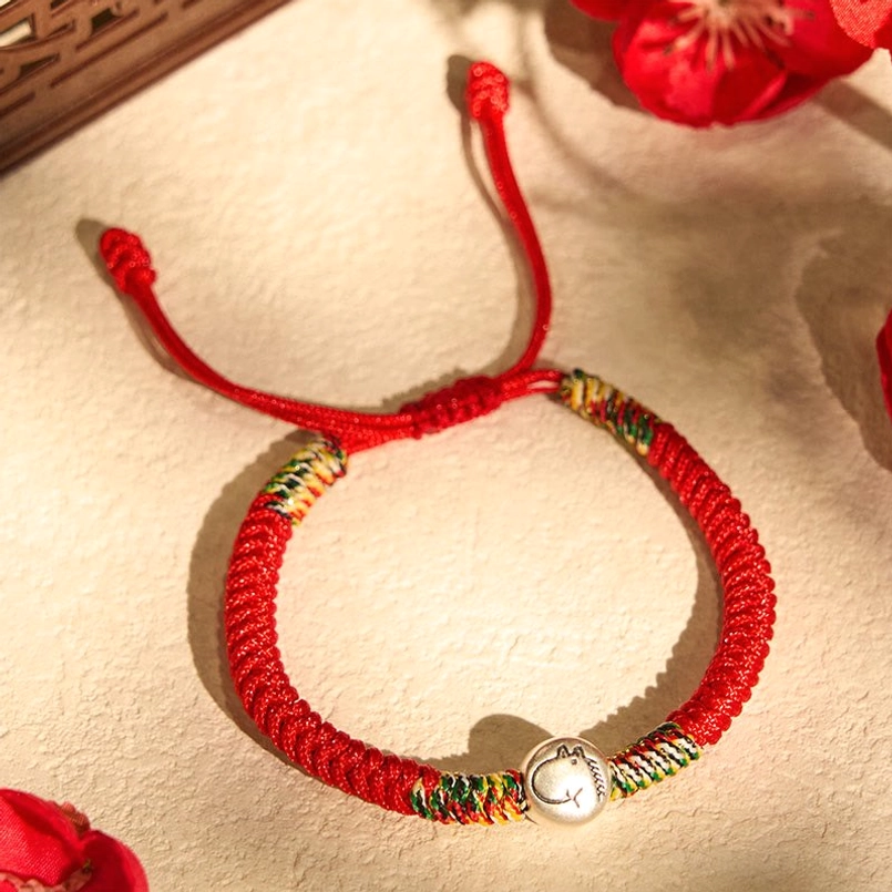 Adjustable drawstring end of Zodiac Horse red string bracelet on beige table