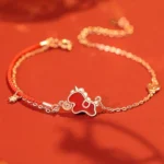 Year of the Horse red string bracelet with sterling silver charm and red agate coin pendant on warm red background