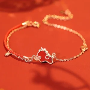 Year of the Horse red string bracelet with sterling silver charm and red agate coin pendant on warm red background