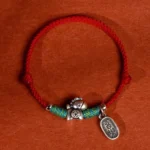 Year of the Horse red string bracelet with sterling silver charm, braided cord with turquoise accents, overhead view