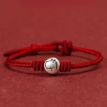 Year of the Horse red string bracelet with 999 sterling silver horse charm, flat lay view on red background