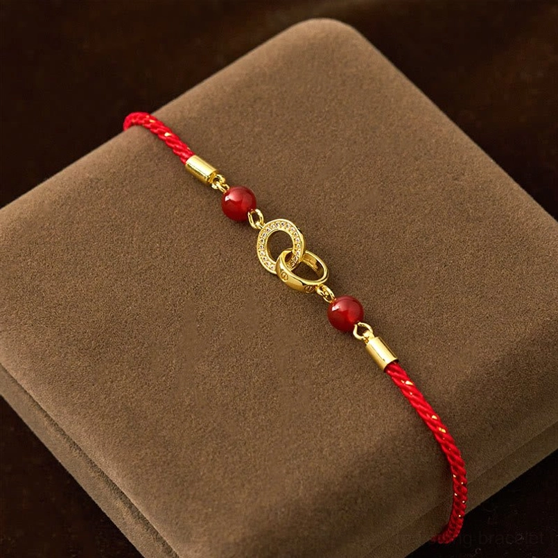 Side oblique view of interlocking gold peace buckle red string bracelet with agate beads