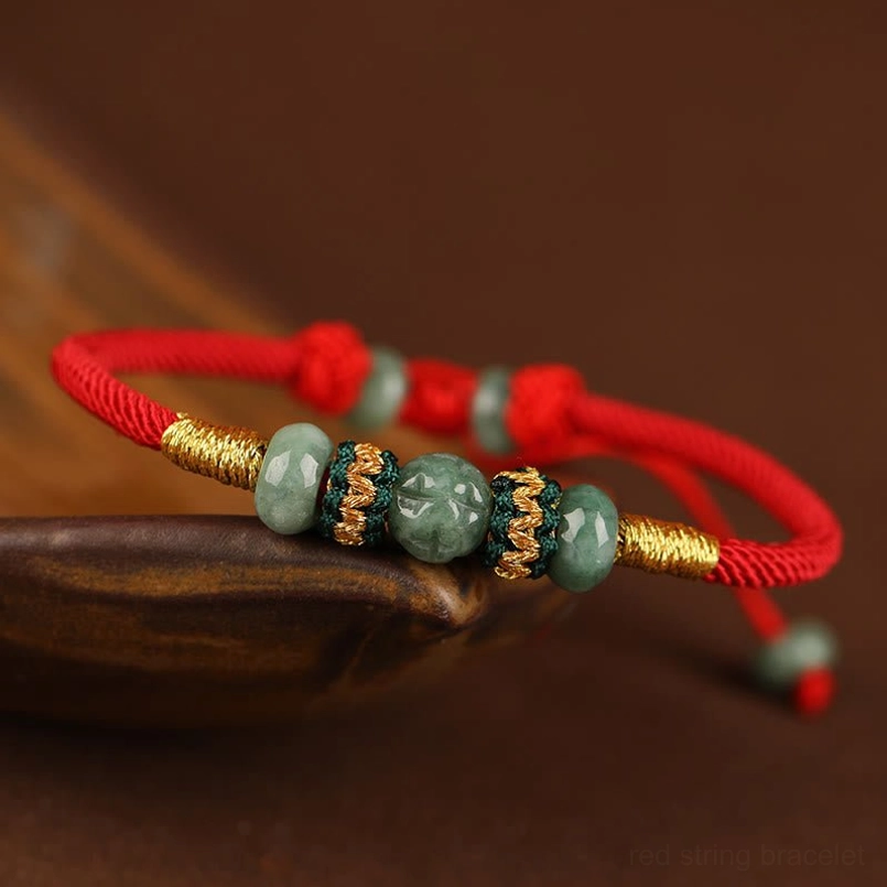 Jade abacus bead prosperity red string bracelet on wooden saucer dark background