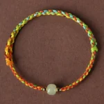 Colorful rope jade abundance bracelet flat lay with multicolor braided cord and green jade bead