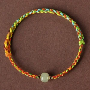Colorful rope jade abundance bracelet flat lay with multicolor braided cord and green jade bead