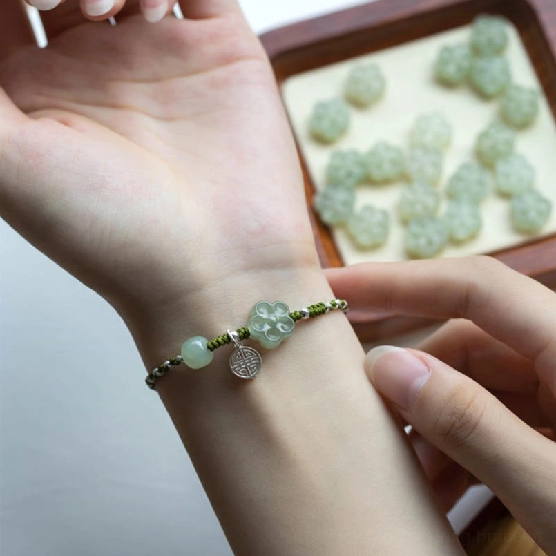 Bracelet component extreme close-up showing jade barrel bead braided rope and metal clasp