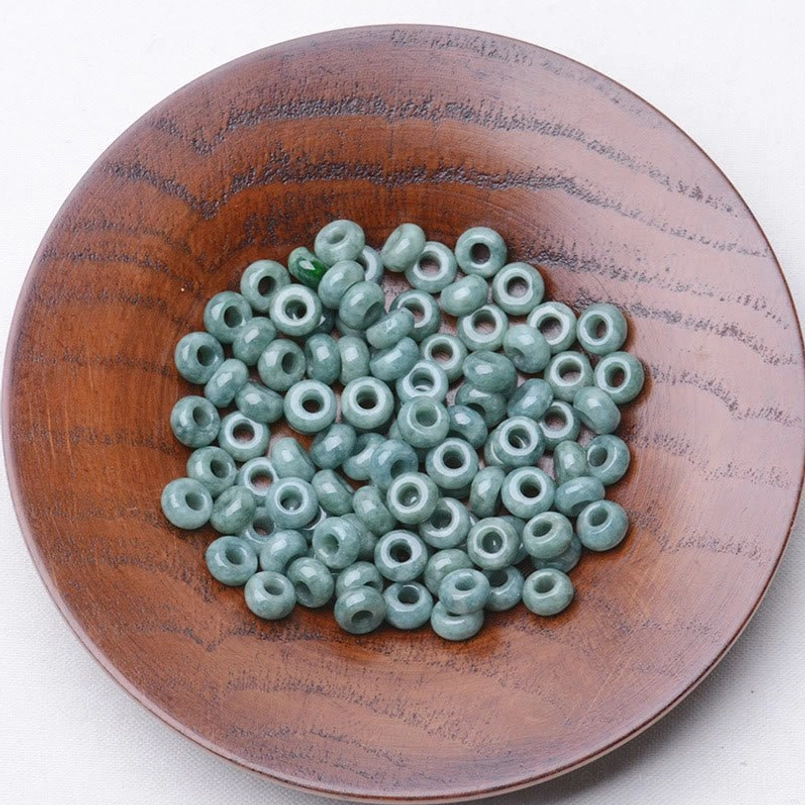 Light green polished jade rondelle beads piled on dark ceramic plate