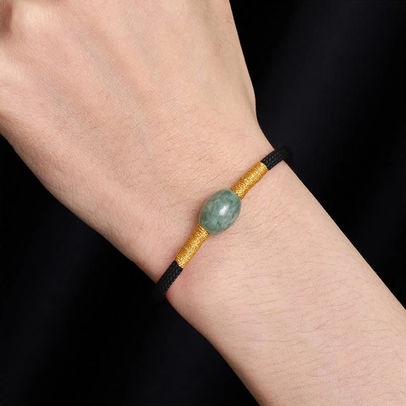 Black braided string jade bracelet worn on wrist with gold accents