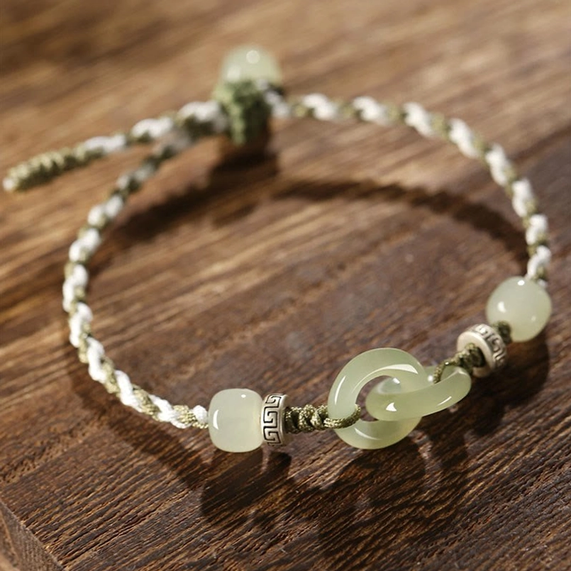 Side perspective of hetian jade peace buckle bracelet with engraved metal beads and braided rope