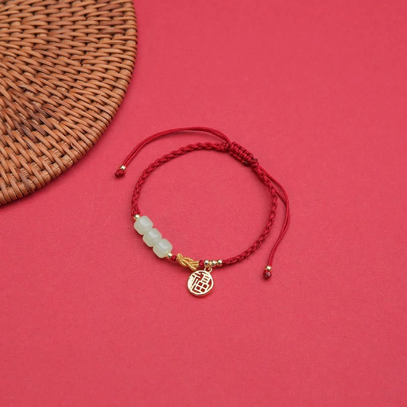 Red string jade bracelet with fu character pendant fitted on fair skin wrist