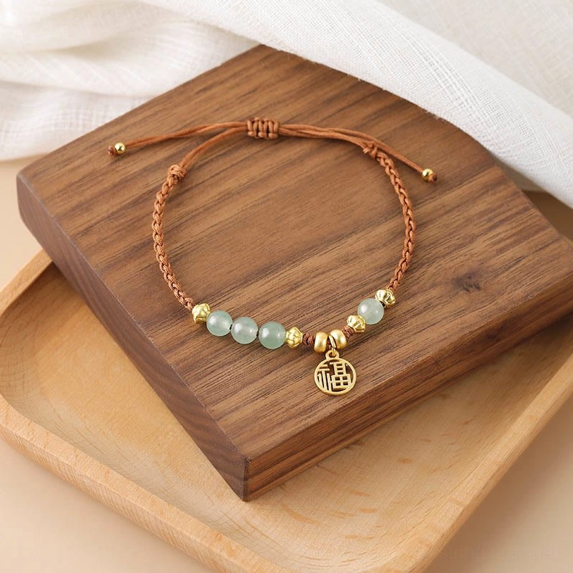 Fu character jade blessing red string bracelet flat lay on wooden tray