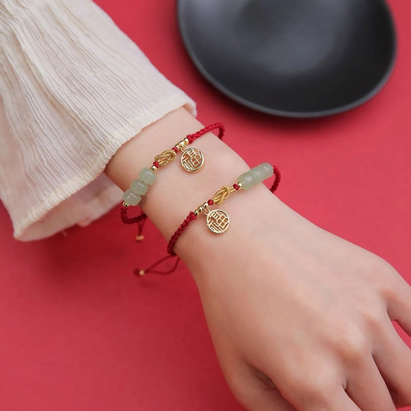 Matching pair of jade fu character red string bracelets worn on both hands together