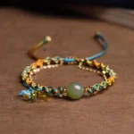 Double-layer jade lucky bracelet flat lay overhead with blue and gold braided cord and green jade bead