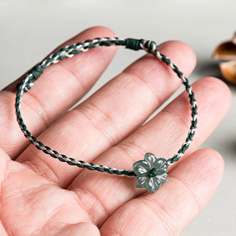 Close up handheld view of jade orchid braided bracelet held in palm
