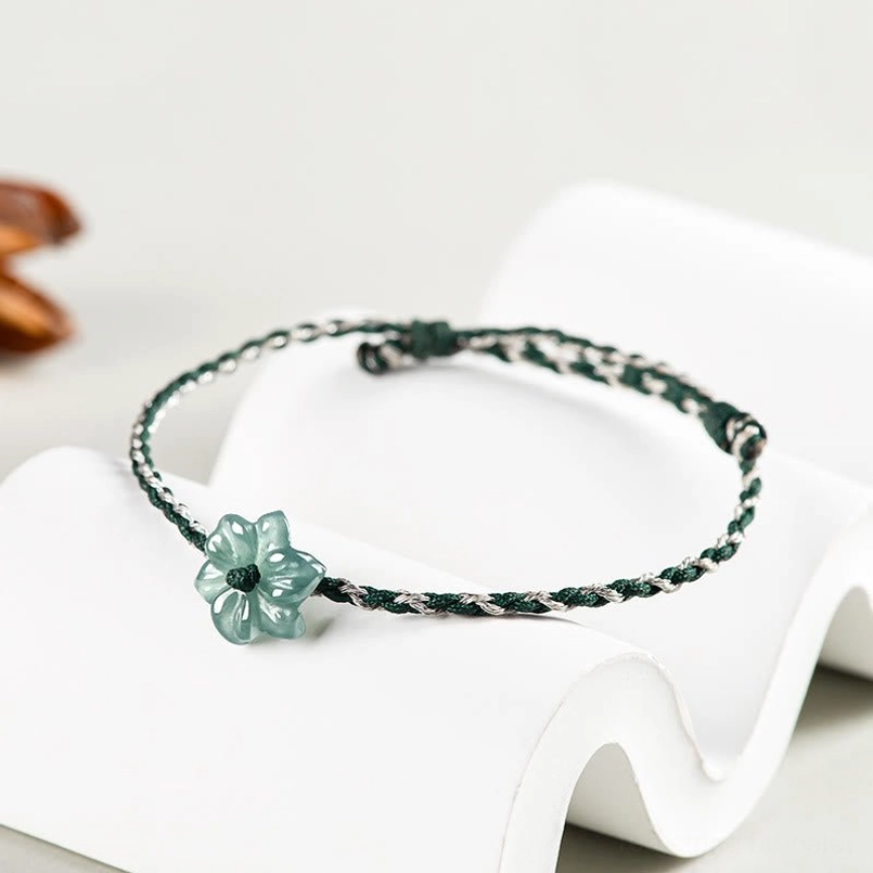Three quarter side view of jade orchid braided bracelet on display stand with dried flowers
