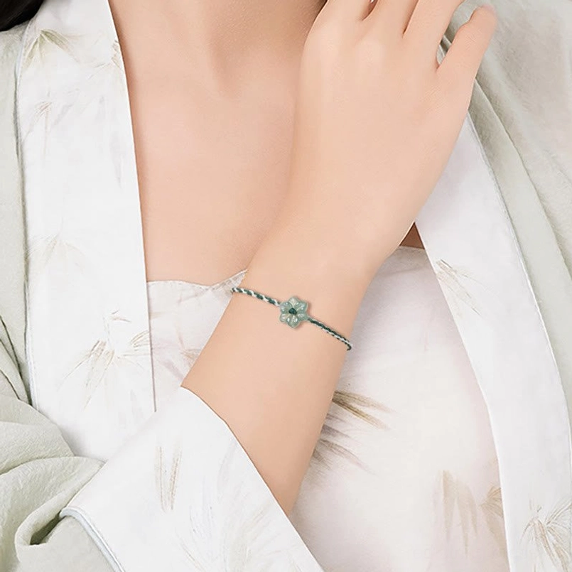 Lifestyle shot of jade orchid green string bracelet worn on wrist with traditional clothing