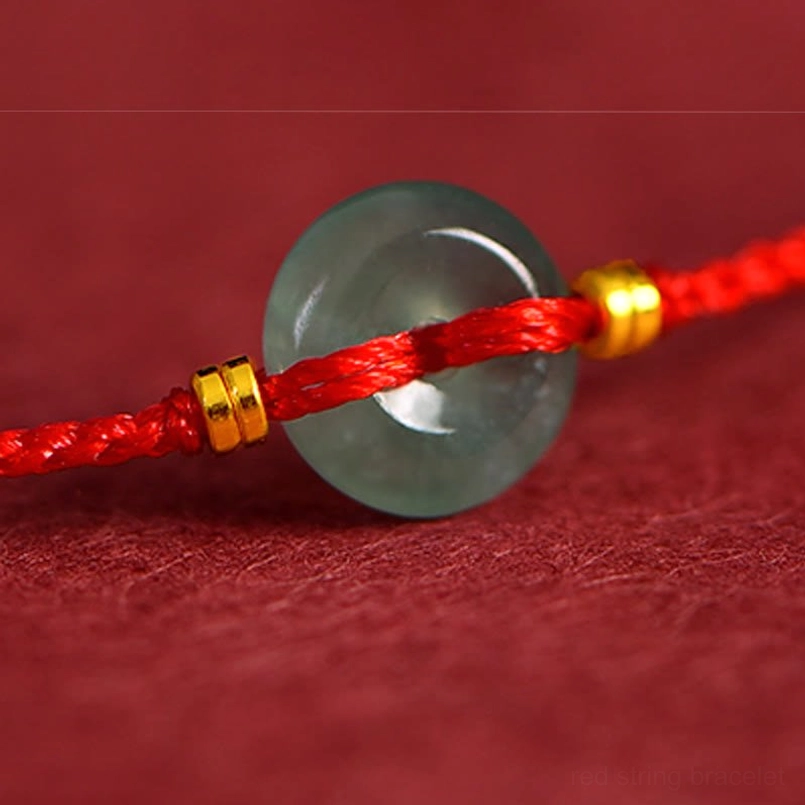 Close-up detail of jade peace buckle red string bracelet - smooth dark green jade with red braided cord and gold beads