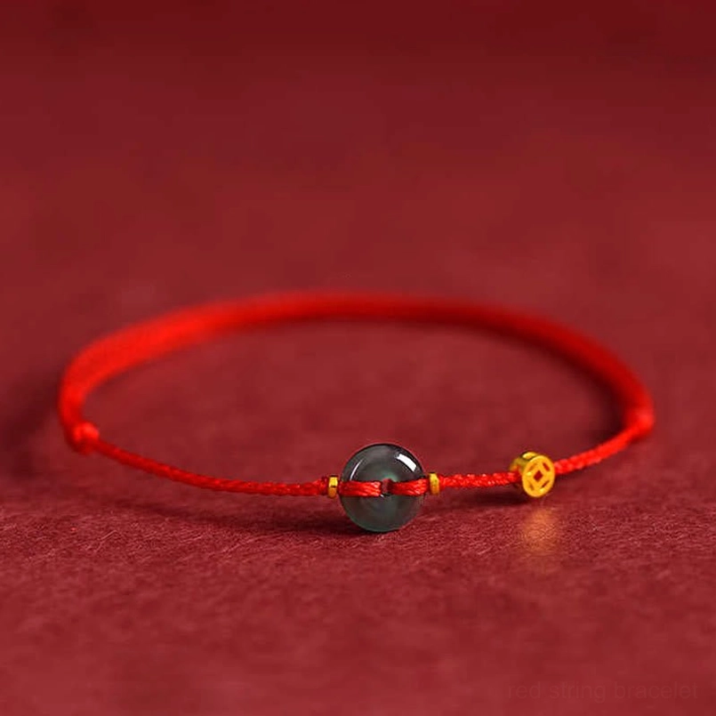 Jade peace buckle red string bracelet with gold copper coin charm on red fabric background - front flat view