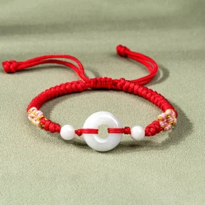 Red jade peace buckle bracelet with gold-thread decorated knots on light gray background